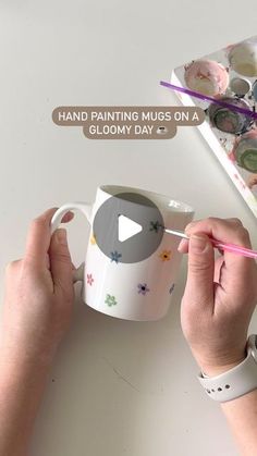 someone is painting on a coffee mug with pink crayons