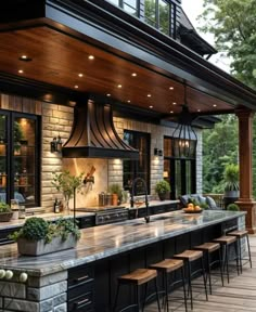 an outdoor kitchen with lots of counter space and lights on the ceiling, along with bar stools