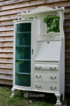 an old dresser is painted white with green glass doors