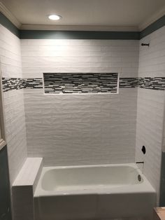 a white bath tub sitting under a window in a bathroom