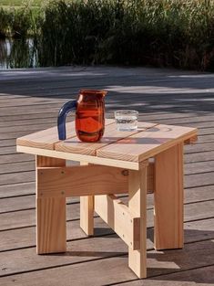 a wooden table with a pitcher on it and a glass sitting on top of it