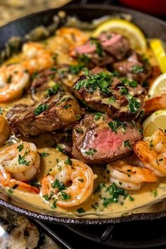 a plate full of food with shrimp, steak and lemon wedges on the side