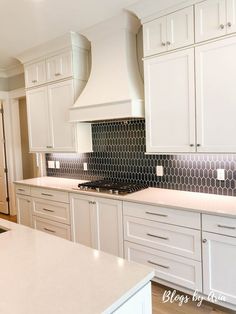 a kitchen with white cabinets and black backsplash tiles on the countertops,