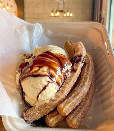 an ice cream sundae with chocolate drizzle and waffles in a paper container