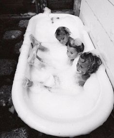 three children are in the bathtub and one is sitting on the side of the house