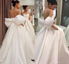 a woman in a white wedding dress looking at herself in the mirror with her back to the camera