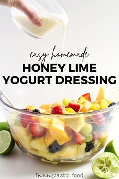 a glass bowl filled with fruit and yogurt dressing next to sliced limes