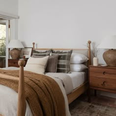 a bed room with a neatly made bed and two lamps on either side of the bed