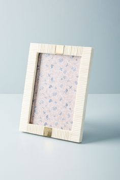 a small white frame with a flower pattern on the front and bottom, sitting on a table