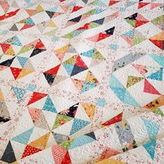 a colorful quilt is laying on top of a tablecloth that has many different colored triangles