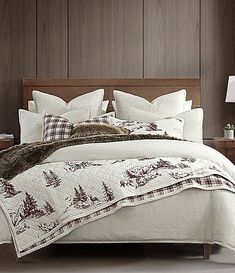 a bed with white and brown comforters in a bedroom next to a night stand