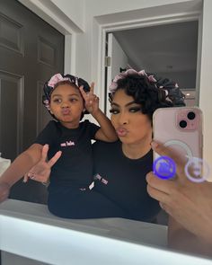 a woman taking a selfie with her daughter in front of a mirror while holding a cell phone