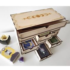 an open wooden box with several different items in it on a white surface next to other boxes