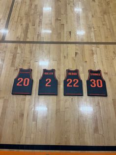 three basketball jerseys are displayed on the floor