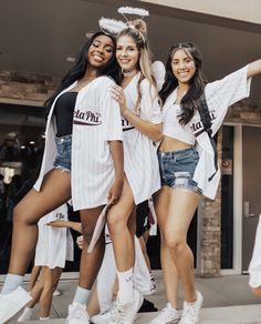 three girls in white shirts and denim shorts posing for the camera with their arms around each other