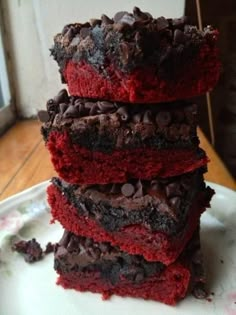 a stack of red velvet brownies sitting on top of a white plate