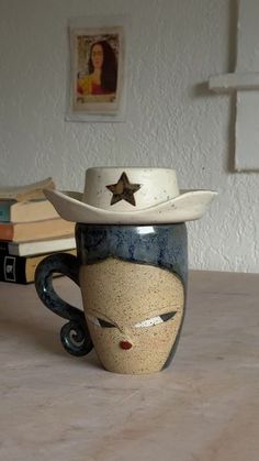 a coffee cup with a cowboy hat on it sitting on a table next to books