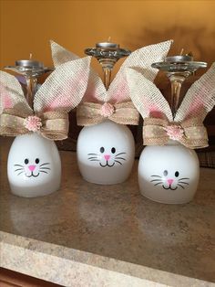 three white vases with pink bows and bunny ears on them sitting on a counter