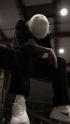 a man sitting on top of a skateboard next to a white hat and black pants