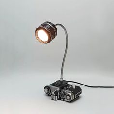 an old - fashioned camera is hooked up to a small lamp on a white background