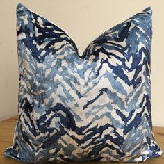 a blue and white pillow sitting on top of a wooden table