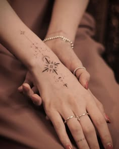 two hands holding each other with tattoos on their fingers and wrist, both showing stars