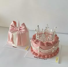 two cakes decorated with bows and tiaras on top of each other, one is pink