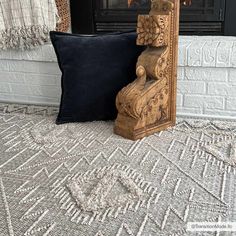 a wooden chair sitting next to a pillow on top of a carpeted floor in front of a fireplace