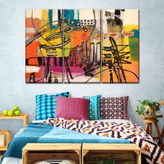 two paintings on the wall above a bed in a room with blue walls and colorful pillows