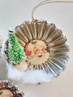 two ornaments with santa clause on them are sitting next to each other and one has a pine tree in it