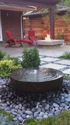 an outdoor fire pit surrounded by rocks and plants