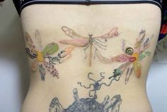 a woman's back with tattoos on her body and dragonflies drawn on it