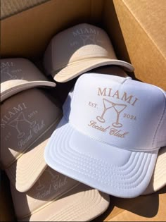 several hats in a cardboard box with the word miami written on one side and an image of a martini glass on the other