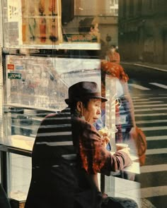 a man sitting on a bench in front of a store window eating an ice cream sundae