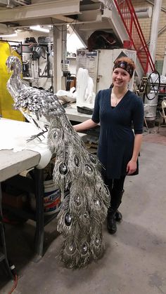 a woman standing next to a peacock statue