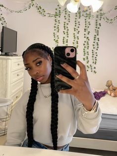 a woman taking a selfie with her phone in front of her head and wearing braids