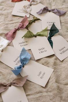 several different colored bows are laid out on a sheet of paper with name tags attached to them