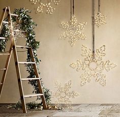 snowflakes are hanging on the wall next to a ladder and christmas wreaths