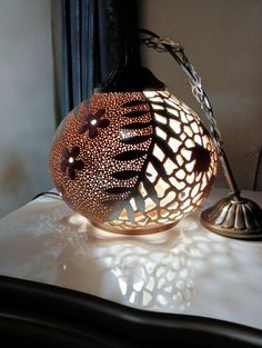 a decorative lamp sitting on top of a table next to a lamp shade with an intricate design