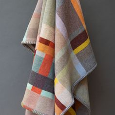 a multicolored blanket hanging up against a gray wall with the top half folded