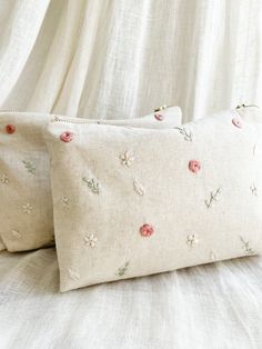 two white pillows with pink flowers on them