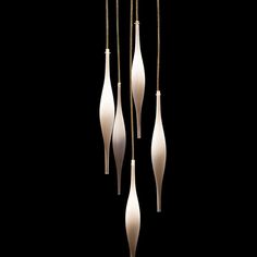 three white vases hanging from strings on a black background