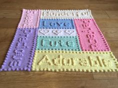 a crocheted afghan with the words love written in different colors and letters on it