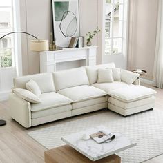 a living room with a white sectional couch and coffee table in front of the window