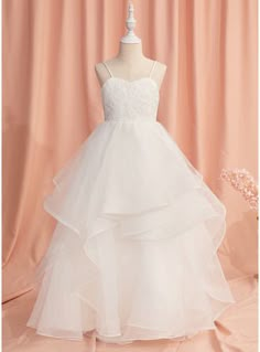 a white wedding dress on a mannequin in front of a pink curtained background