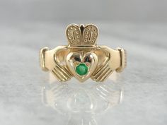 A pretty, shining emerald has been set perfectly just in the center of this vintage ring. The color of the gold, rich and warm, is a perfect counterpoint to this lovely stone.Betrothal rings depicting two clasped hands date back many centuries in European history. The Irish version, the Claddagh ring, came about in the 1600's and has been produced continually since that time. Metal: 14 Karat Yellow GoldCrown To Heart Width: 14.5 mmGem: EmeraldGem Measurement: 2.88 mm, roundMarks: Although not st Antique Yellow Gold Emerald Ring, Antique Emerald Ring In Yellow Gold, Classic Rings With Polished Finish For May Birthstone, 14k Gold Green Ring With Polished Finish, Timeless Gold Diamond Ring For May Birthstone, Collectible 14k Gold Emerald Ring, Collectible Green Emerald Ring In 14k Gold, 14k Gold Emerald Ring With 17 Jewels - Collectible, Green 14k Gold Emerald Ring Collectible