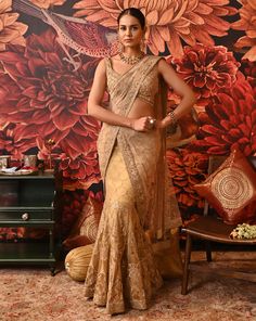 This authentic Layla saree is a one-of-a-kind attire that exudes glamour and modernity. The fishtail drape on the skirt adds a contemporary twist to your classic saree. The vivid embroidery details highlighted with beads are fascinating along with the attached sheer pallu. The sleeveless blouse is heavily accentuated with beads and sequins. A great show-stealer with a style so surreal. Heavily embellished cross-band sleeveless gold-foil printed blouse with centre back hook opening Fish-cut Saree with embroidered applique work with dabka and nakshi at the border of the pallu Side zip closure in the saree. From Moledro’s Riwayat collection. DELIVERY TIMEPlease allow 8-12 weeks for your outfit to arrive. FABRIC DETAILSSaree - Butterfly Net, Zari BrocadePallu - Butterfly NetBlouse - Cotton Sil Transitional Tissue Silk Pre-draped Saree, Tissue Silk Pre-draped Saree With Dupatta, Gold Pre-draped Saree For Reception, Navratri Floor-length Dola Silk Pre-draped Saree, Festive Raw Silk Pre-draped Saree, Transitional Pre-draped Chanderi Saree With Sheer Dupatta, Floor-length Pre-draped Saree With Dupatta, Traditional Drape Chanderi Saree For Designer Wear, Cutdana Pre-draped Saree For Reception And Diwali