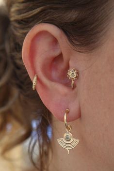 a close up of a person wearing gold earring designs on their ears and nose