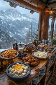 a wooden table topped with plates and bowls filled with food next to a large window