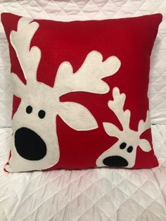 a red and white pillow with two reindeer heads on it